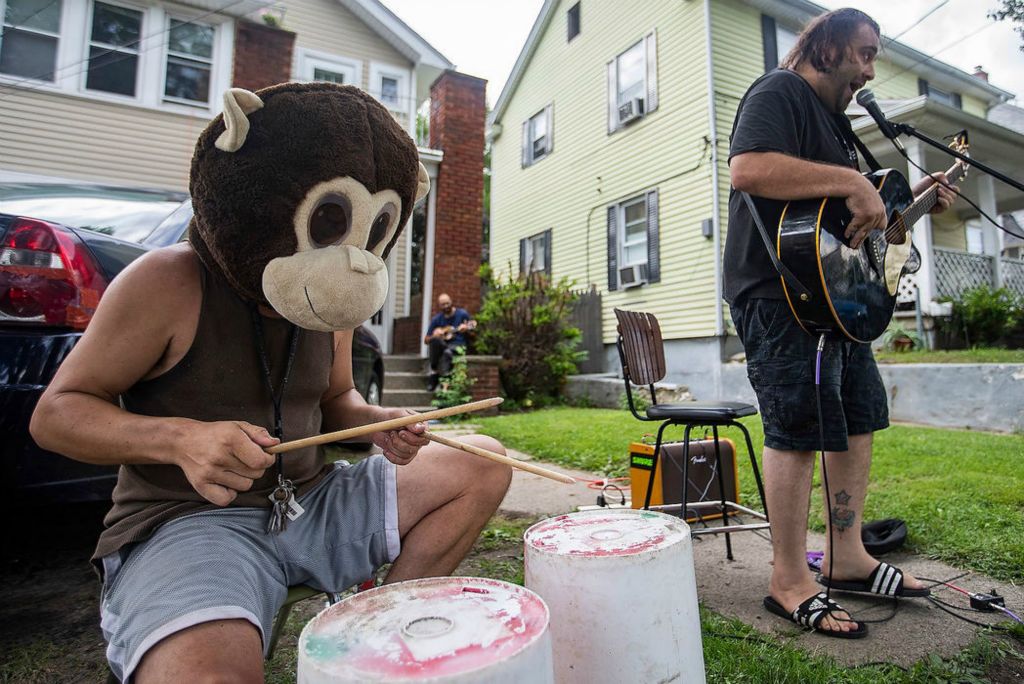 Feature - 3rd place - Richard Surprise (left) wears a monkey mask as he plays the drums while Brad Pace plays the guitar on Jackman Road in Toledo. Surprise and Pace decided to play music outside for the traffic passing by, but to also promote Richard's business, Lawn Greetings Toledo.  Rebecca Benson / The Blade