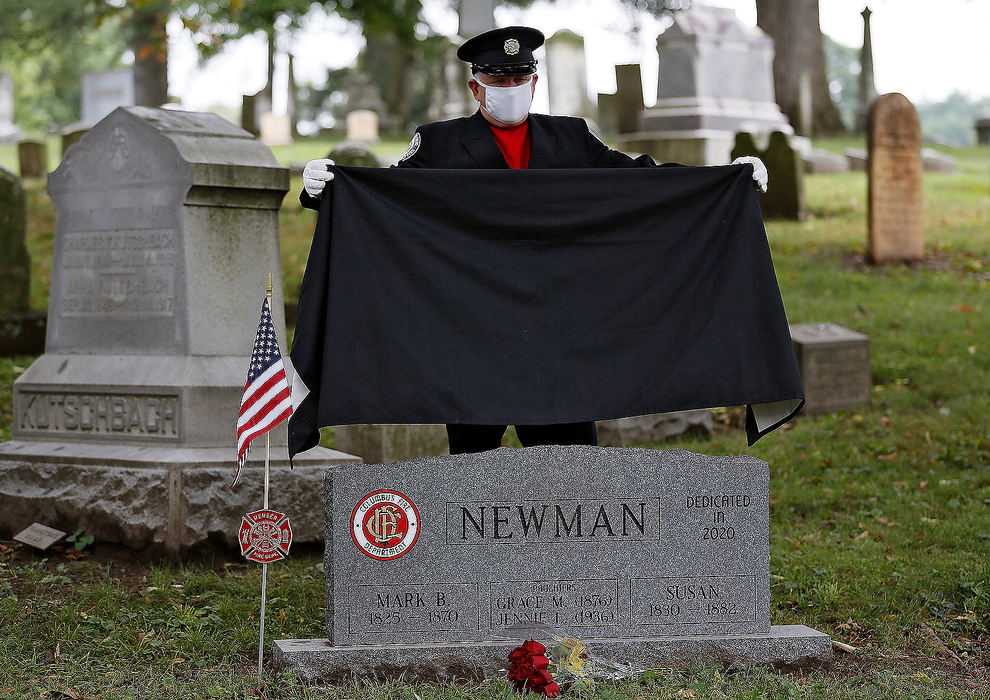 General News - 1st place - The Columbus firefighter Stephen Cox reveals the grave of Columbus firefighter Mark B. Newman during a ceremony at Greenlawn Cemetery in Columbus. On August 4, 1870, Newman was killed by a collapsing wall while assisting in fire suppression activities at the Columbus Woolen Factory. Newman has been recognized as the first Columbus Firefighter to die in the line of duty.  Kyle Robertson / The Columbus Dispatch