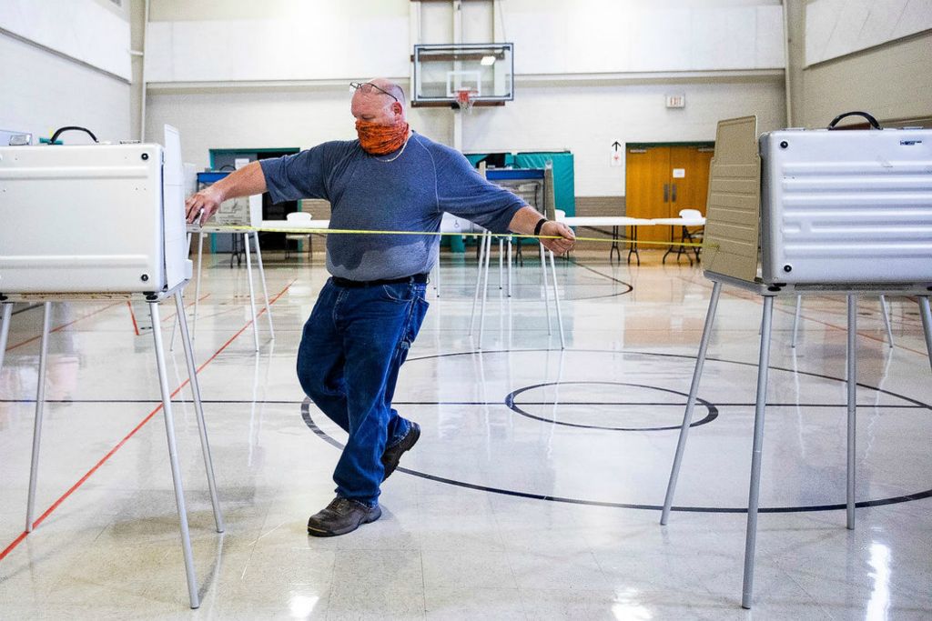 General News - 2nd place - Patrick Thatcher uses measuring tape to measure 6 feet in between voting booths to enforce social distancing while setting up a polling place for the Michigan primary election at St. Luke's Lutheran Church in Temperance, Michigan. Rebecca Benson / The Blade