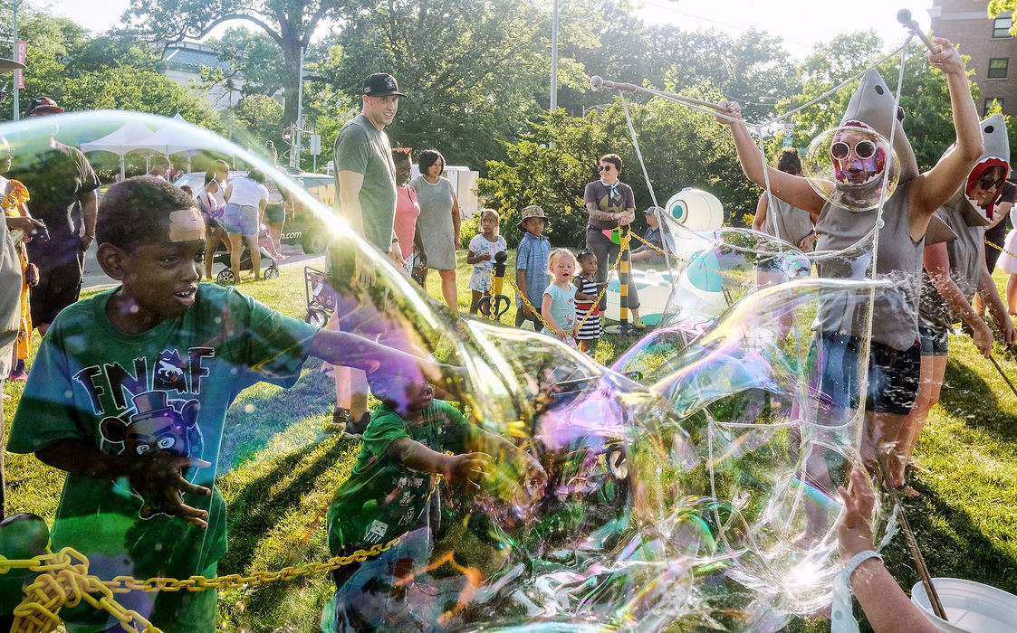 Feature - 1st placeLindsay Williams of the Bubble Sharks creates bubbles for children including Jamar Taylor, 9, of Toledo (left) during the TMA Block Party in Toledo. The Bubble Sharks are performance artists who dress in shark costumes and play with giant bubbles at community events, like Art Loops at the TMA Block Party.  (Jeremy Wadsworth / The Blade)