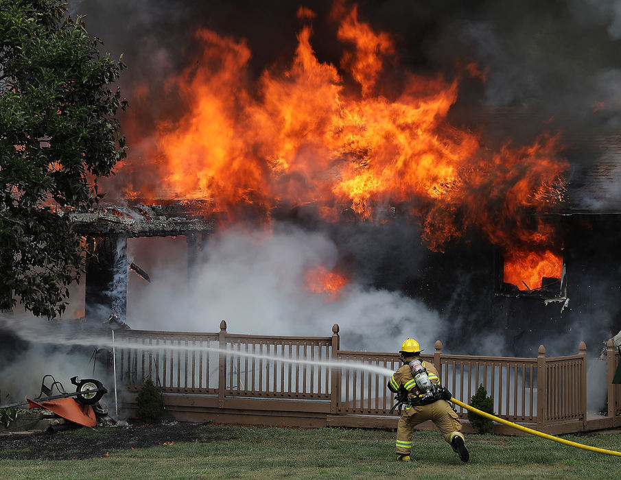 Sports Feature - 3rd placeA Moorefield Township firefighter rushes into position to attack a fully engulfed house fire soon after arriving on the scene on Thomaston Trail Thursday. The homeowners were not home at the time of the blaze.  (Bill Lackey / Springfield News-Sun)