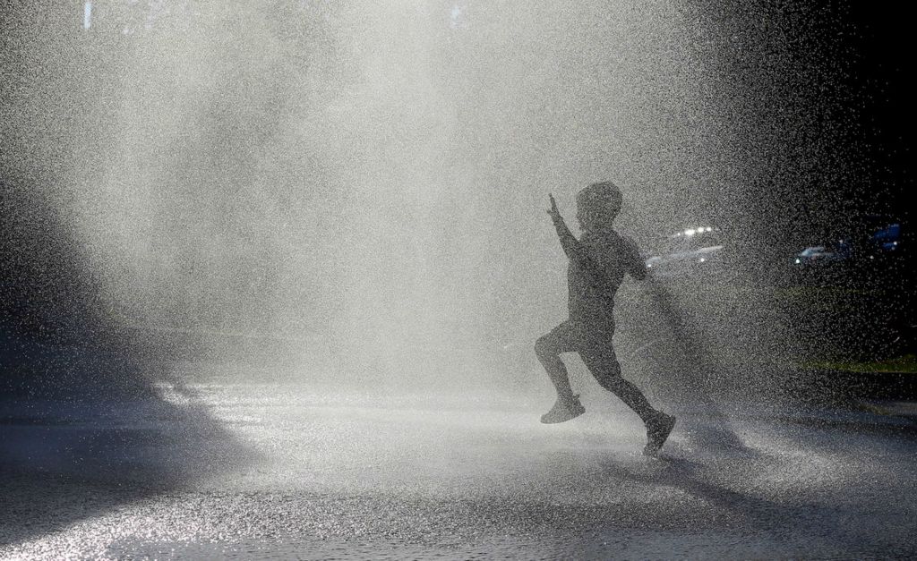 Feature - 1st place - A child plays in the mist from a Stow firetruck during the National Night Out festivities at the Stow Police and Fire Station. (Jeff Lange / Akron Beacon Journal)