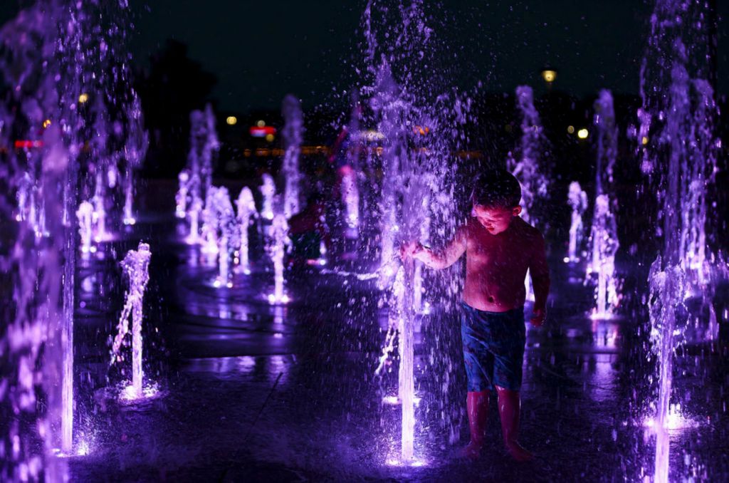 Feature - 2nd place - Rylee Bahrs, 3, of Toledo plays on a splash pad which is lit for night time activity at Promenade Park in Toledo.  (Jeremy Wadsworth / The Blade)