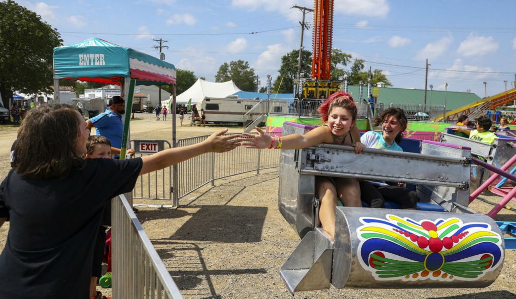 General News - 3rd place - At center Ariana Levario, 15, of Fremont reaches out and slaps five to Lucian Doty, 13, of Fremont while riding the Scrambler during the 169th Sandusky County Fair in Fremont. At right Reyna Guardiola, 15, of Fremont looks on.  (Jeremy Wadsworth / The Blade)