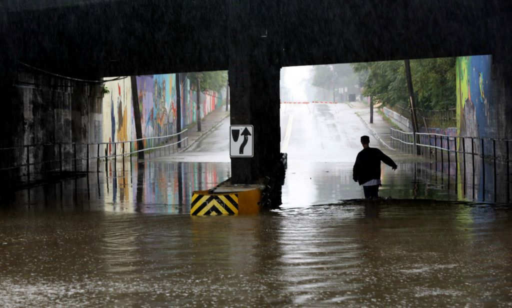 Spot News - 1st place - Ernest Rasar crosses the water to get to the other side of East Broadway St. toward Vinal St. during a rain storm on August 18, 2021.  (Amy E. Voigt / The Blade)