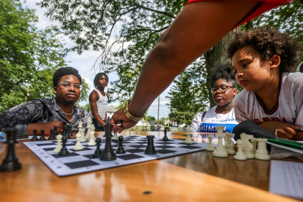 Feature - 2nd place - Toledo resident Lakes Hendricks, from middle left, waits for Keith Carswell to make his move while Jade Woodley, 16, and Tony Rome, 8, watch the chess match during a National Night Out event aimed to build stronger relationships between the community and fire and police departments at Frederick Douglass Center in Toledo. (Isaac Ritchey / The Blade)