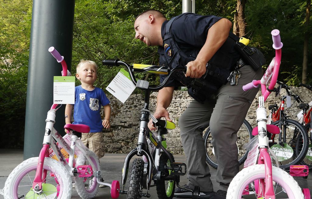 Feature - 2nd place - Springfield Police Officer Zach Massie asks Theo Wilson-Rector, 3, if he's sure he wants the bike he picked out as he plays with the young bicycle raffle winner during the National Night Out at Veteran's Park.  (Bill Lackey / Springfield News-Sun)