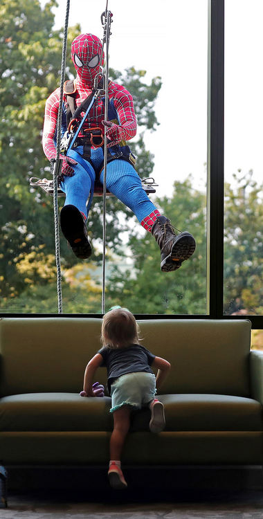 General News - 1st place - Charlie Vallely, 2, of Brookfield (bottom) climbs up on a lobby couch to get a closer look at Spiderman as he makes his way down the side of Akron Children’s Hospital. (Jeff Lange / Akron Beacon Journal)