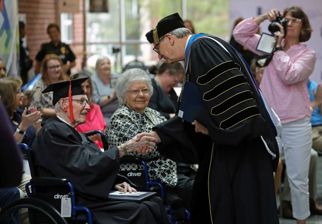 General News - HM - Robert Greathouse, 93, (left) shakes hands with President Gary Miller after receiving his Associate of Technical Studies degree during a ceremony at the University of Akron College of Arts and Sciences. (Jeff Lange / Akron Beacon Journal)