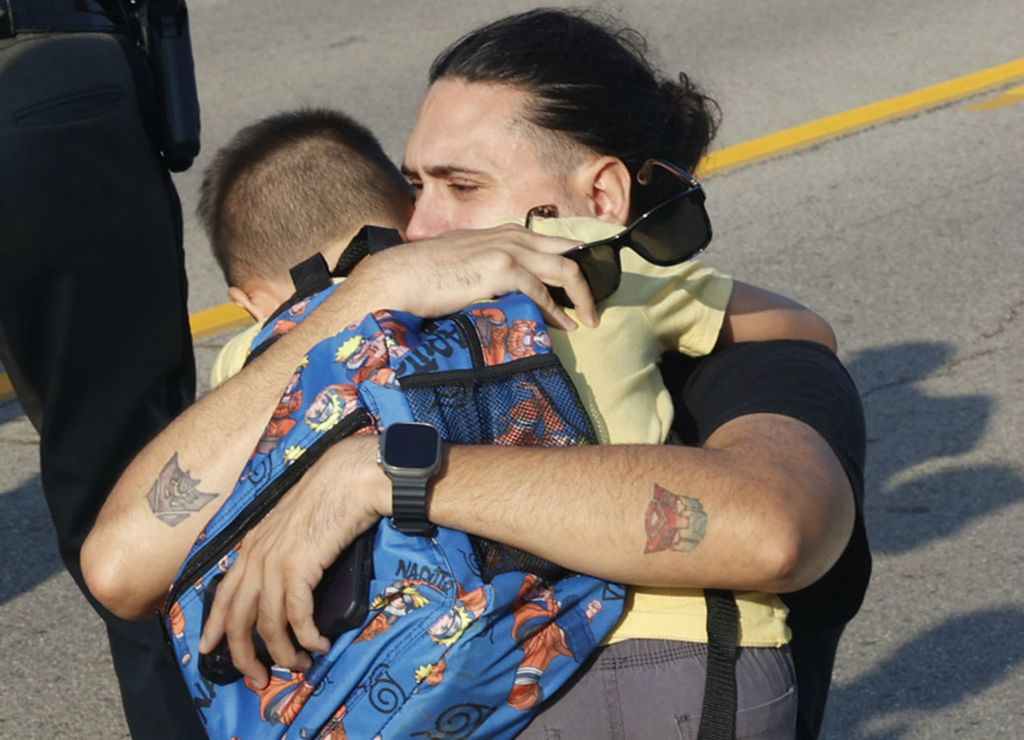 Spot News - 1st place - A father hugs his son at the scene of a Northwestern School District bus crash that killed one student and injured more than 20 others on State Route 41 near Springfield. The bus, carrying 52 elementary students on their way to the first day of school was struck by a mini van and rolled over.  (Bill Lackey / Springfield News-Sun)