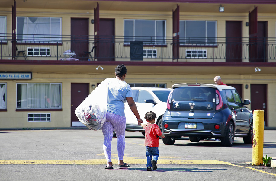 General News - 1st place - Toni Carter-White and her son carry their belongings in a bag as they are forced to leave the Executive Inn homeless shelter by the Springfield Police Department. The shelter was shut down after the Springfield City Council voted the day before to reject a funding plan for the shelter.  (Bill Lackey / Springfield News-Sun)   (Bill Lackey / Springfield News-Sun)