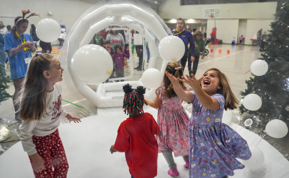 December - Feature - 2nd place - Seven-year-old Ava Heintz (right) plays with balloons inside of an inflatable igloo during The Ability Center’s Jingle Bell Bash in Sylvania. (Jeremy Wadsworth / The Blade)