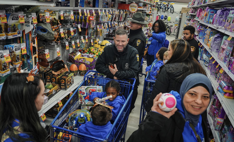 December - General News - 1st place - Toledo Police Officer T.J. Burzynski helps children from the Clever Bee Academy shop for toys during the annual 12 Kids of Christmas event at Meijer on Alexis Road in Toledo. About 75 kids were given  a $100 gift card to shop for toys with police officers. (Jeremy Wadsworth / The Blade)