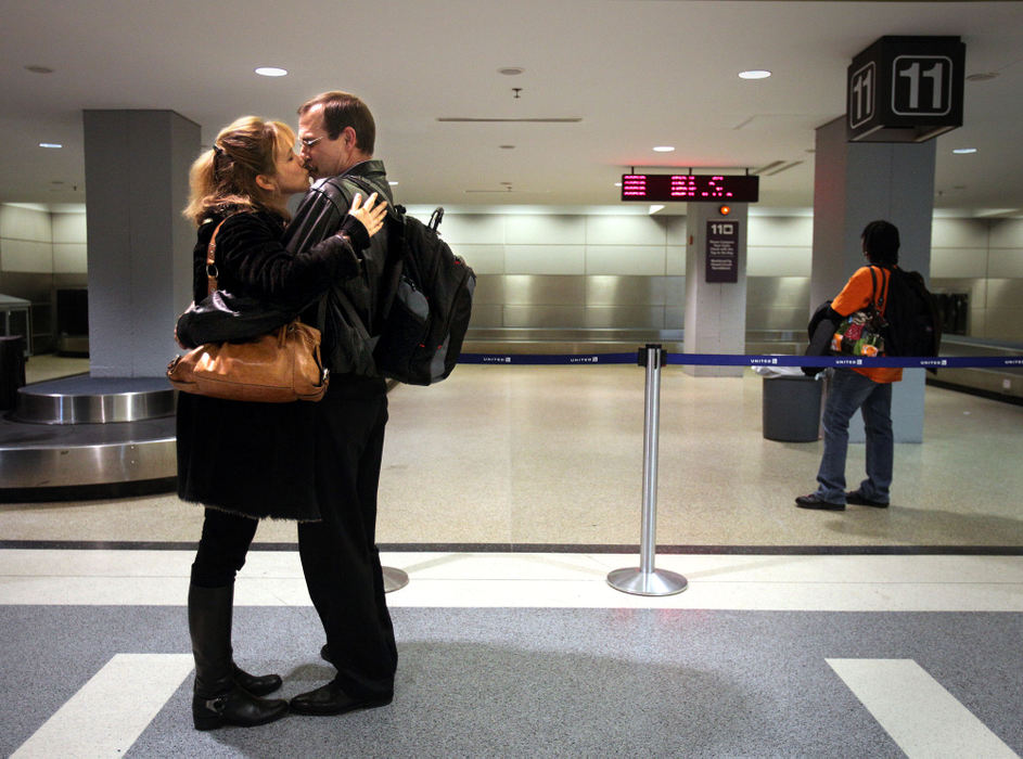 Feature - 1st place - Jeanne Martanovic, 47, of Cleveland Heights (left) kisses John Goentzel, 53, of Marion, Kansas, as they meet for the very first time as Goentzel got off his plane at Cleveland Hopkins International Airport. The two met on an online dating site called Catholic Singles and decided it was time to meet each other in person for Christmas.  (Lisa DeJong / The Plain Dealer)