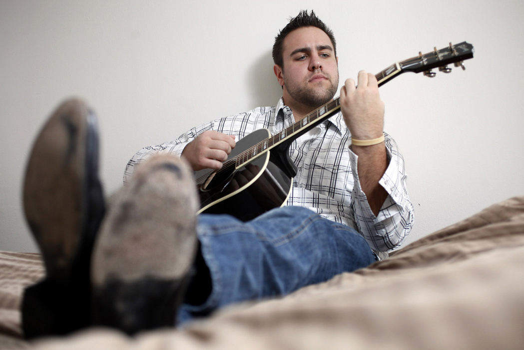 Portrait - 1st place - Ohio State defensive tackle Evan Blankenship plays his 2011 Gibson Hummingbird Pro guitar in his room at Olentangy Commons.  (Shari Lewis / The Columbus Dispatch)