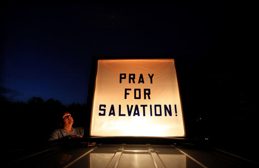 Feature - 3rd place - Nancy Bytnar, 50, makes sure her lighted sign is secure on top of her minivan. Her husband Steve built the lighted sign out of a high-beam truck headlight, Plexiglass and scrap from the garage. Bytnar, a life-long resident of Rootstown, is one of the many believers worldwide that Judgment Day is May 21, 2011.  (Lisa DeJong / The Plain Dealer)