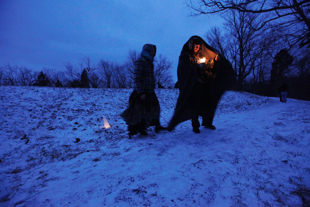 Feature - 2nd placePaul Kellogg, of Traverse City, Michigan, uses his blanket to shield his candle's flame from blustery winds as he and Jourdan Musnicky (left) light candles in bags outlining the Serpent Mound. People formed a circle for a ceremonial lighting ceremony and lit their candles for the annual "Lighting the Serpent" event at Serpent Mound State Memorial near Peebles, Ohio in Adams County. (Fred Squillante / The Columbus Dispatch)