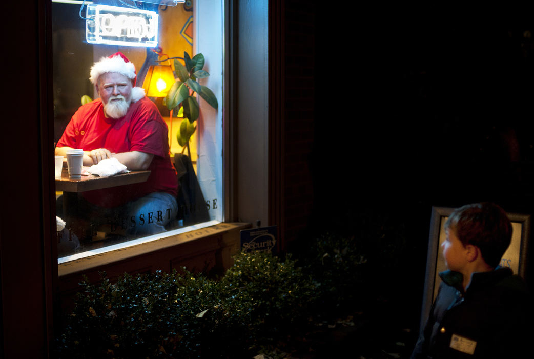 Feature - 3rd placeFive-year-old Henry Pitts, (right) of Bexley, slows down as he catches a glimpse of Tim Shrewsbery, (left) of Columbus, having a drink at the Cup O' Joe on South Third Street during the Village Lights event in the German Village. Shrewsbery said he comes down to the Cup O' Joe every Sunday and thought it was pretty funny all the attention he was getting as families walked by the coffee shop's windows, some even stopping to pose for photographs. Crowds of people explored the German Village Sunday evening as shops stayed open late and more than 10,000 luminaries snaked around the streets.  (Eamon Queeney / The Columbus Dispatch)