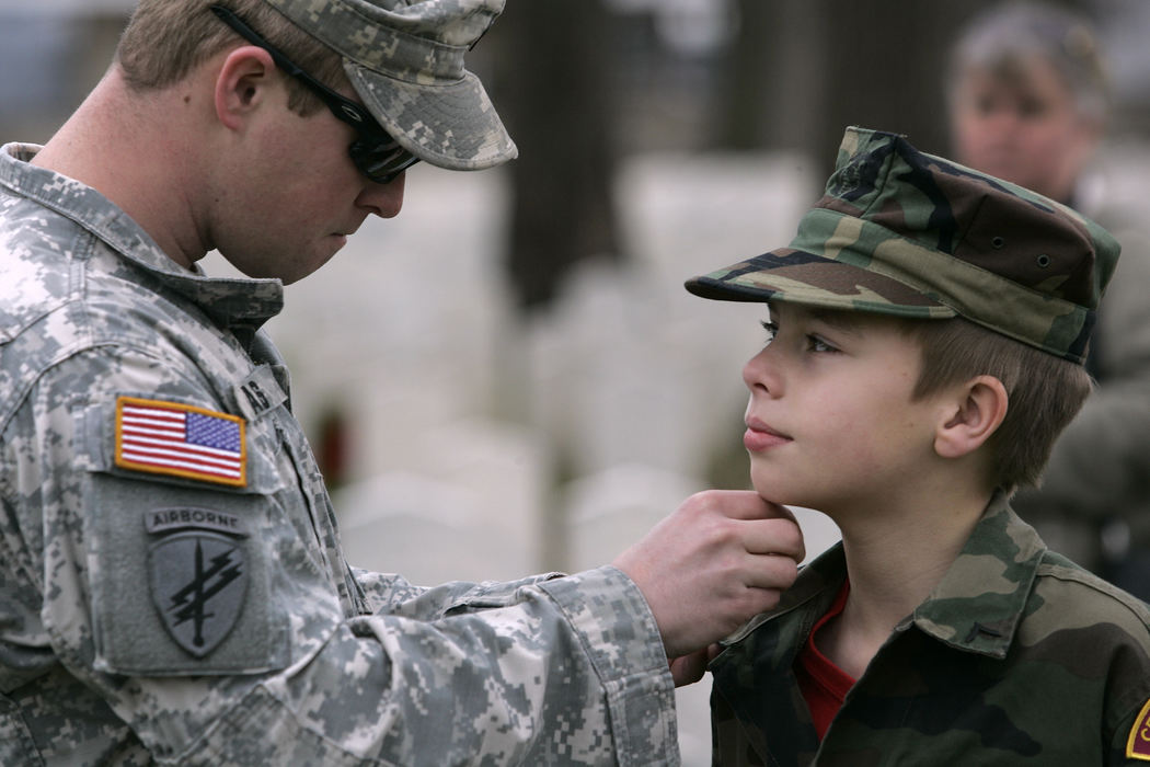 General News - 1st placeArmy Specialist Damon Haas, (left) of the 403rd Civil Affairs Battalion of Utica, NY, adjusts his brother William Saunders', 10, a member of the Young Marines, rank insignia after placing wreaths to honor fallen soldiers of the Civil War during a Wreaths Across America event. (Thomas Levinson / The Columbus Dispatch)