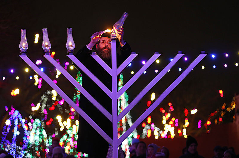 Feature - 2nd place - Rabbi Levi Andrusier lights a menorah at the Columbus Zoo and Aquarium.  This event marked the first time Hanukkah was celebrated at the zoo according to Becca Nitzberg, outreach director for the Jewish Community Center of Greater Columbus .   (Chris Russell / The Columbus Dispatch )