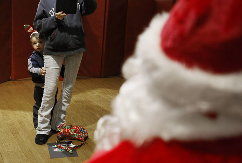 Feature - 3rd place - Damian Starkey takes cover behind grandma Kristina Thomas while she snaps a picture of her granddaughter Brooklynn Muncy with Santa at the Schiller Recreation Center in Columbus. Damian finally sprinted up and told Santa he needed toys before making a hasty exit.  (Eric Albrecht / The Columbus Dispatch )