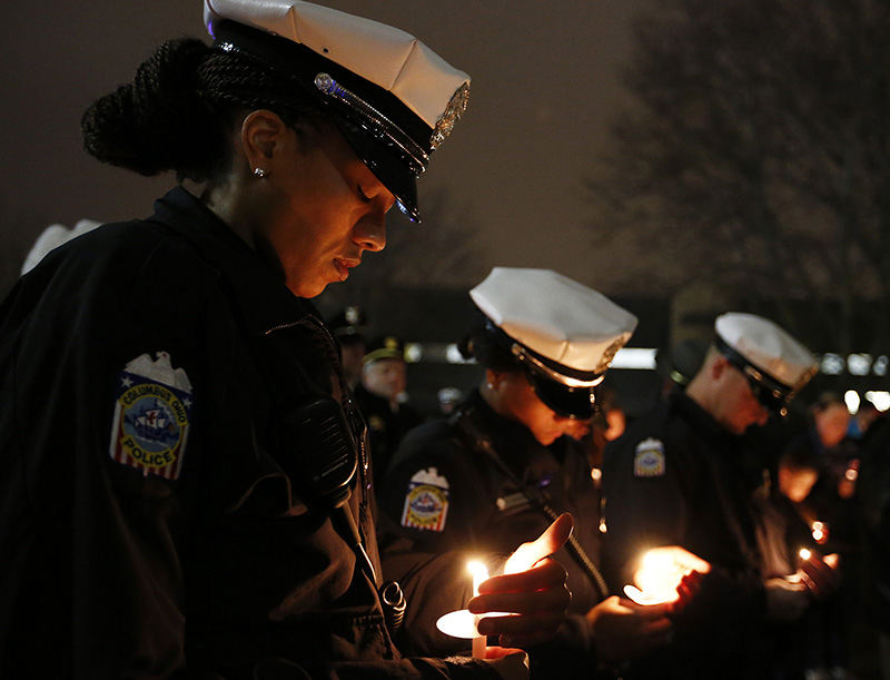 General News - 1st place - Patrol officers and partners Krisha Green (left) and Charmaine Drake of the Columbus Police Department hold candles during a vigil for two slain New York City police officers Dec. 23 at the Columbus Police Memorial.  (Barbara J. Perenic / The Columbus Dispatch )