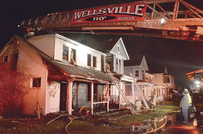 Spot News - 2nd place - The bright, cheerful Christmas lights on a neighboring house are in strong contrast to the fire-blackened exterior of 809 Broadway and the fire-torn exteriors of the houses at 807 and 805 visible as firefighters continue working to douse all of the hidden fire hot spots in the houses. (Patricia Schaeffer / The (Lisbon) Morning Journal)