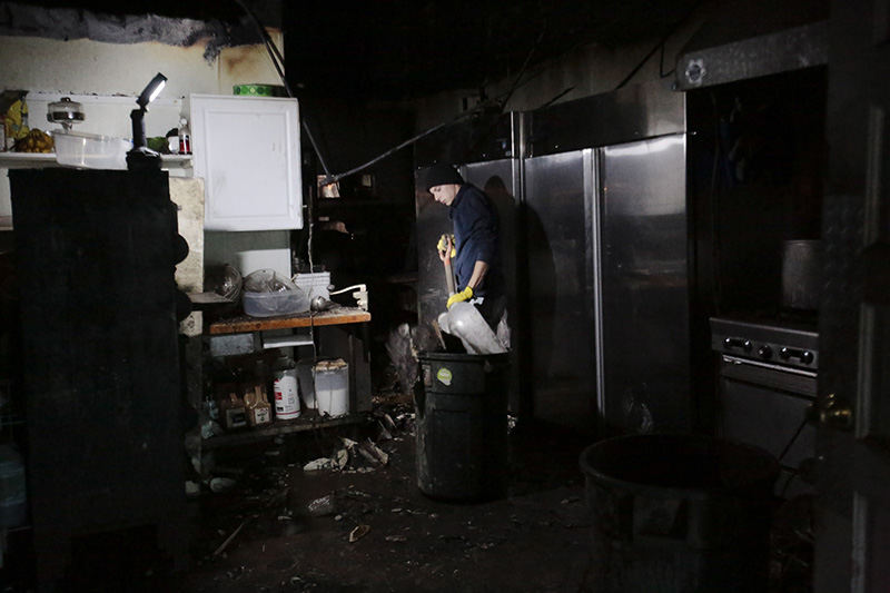 Spot News - 3rd place - Cajun Funk dumps refuse into a trash can while doing cleanup work after a fire destroyed the interior of the Wigwam Restaurant in Canal Winchester. The electrical fire started between the first and second floors of the building on the southwest corner of High and Waterloo streets and damaged the Wigwam as well as Rex's Barbershop and the Barber Museum. (Joshua A. Bickel / ThisWeek Community News)