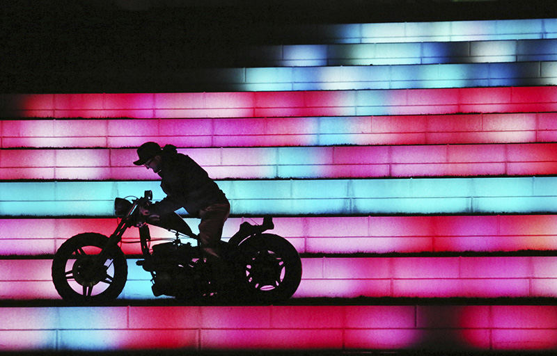 Feature - HM - Garret Wassmuth positions his cycle in preparing to take a photo of it at COSI (in ground lighting makes the steps turn different colors). Several motorcyclists stopped at COSI to take advantage of the warm weather to take shots of their cycles .  (Eric Albrecht / The Columbus Dispatch)