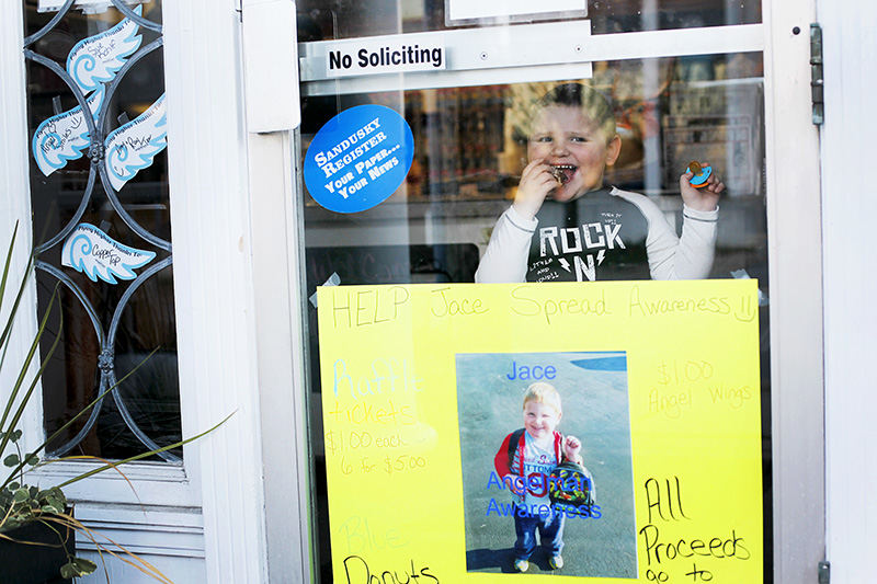 Feature - HM - Jace Meggitt, 4, enjoys a treat at Copper Top Bake Shop as he looks out the window in Bellevue. The bakery is raising money and awareness of Angelman's Syndrome, a neuro-genetic developmental disorder that Jace has been diagnosed with. (Angela Wilhelm / Sandusky Register)