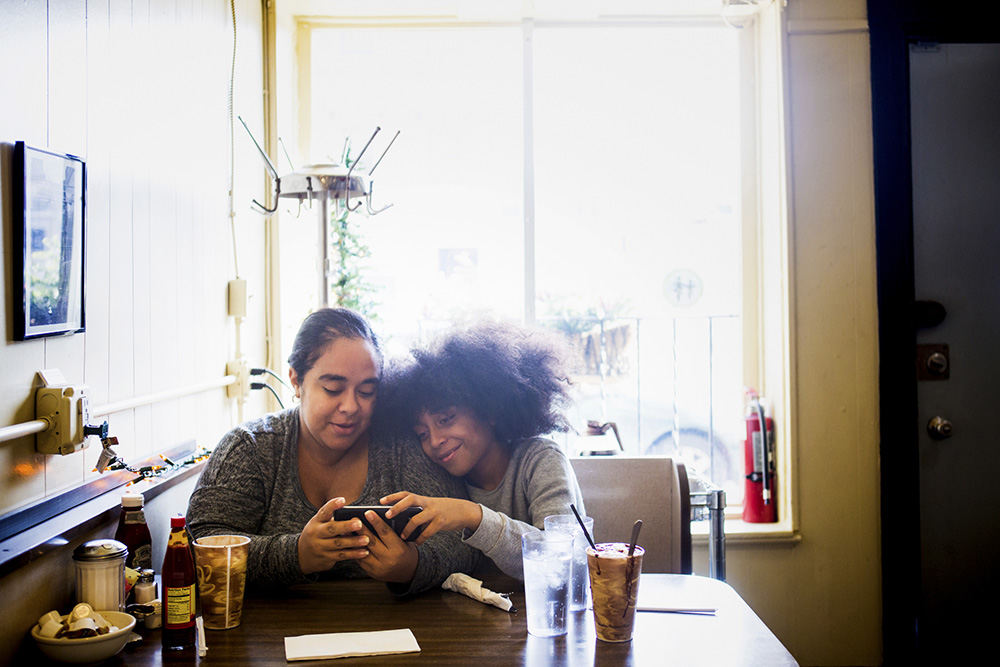 Feature - HM - Renee and Kameron Laguna of Prospect Hill play a game together, while waiting for their breakfast at Tucker's Restaurant on Vine Street. Tucker's reopened in October, after being closed since July 2015 due to fire damage. (Meg Vogel / Cincinnati Enquirer)