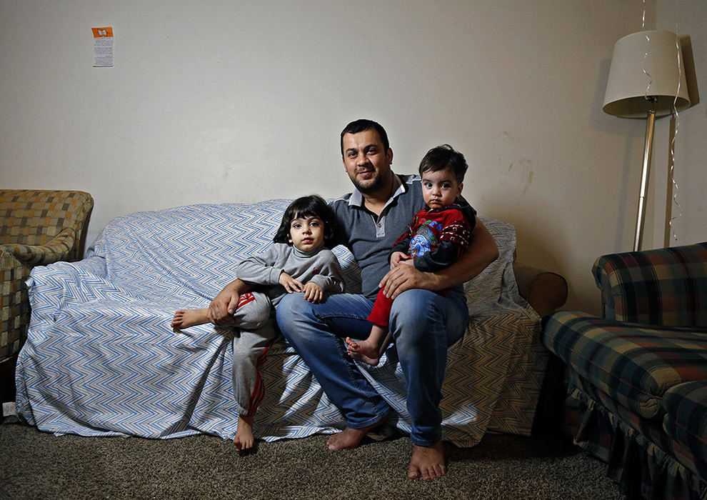 Portrait - 1st place - Alaa Qamar holds his two sons Hussein, 4, left, and Abas, 1, right, in their apartment in Columbus.  Not in the photo is his wife, Nisreen. Qamar and his family arrived here in Columbus in September from Baghdad.  Qamar was former Badhdad policemen for seven years and the process to get over to the United States took over 4 years.  (Kyle Robertson / The Columbus Dispatch)