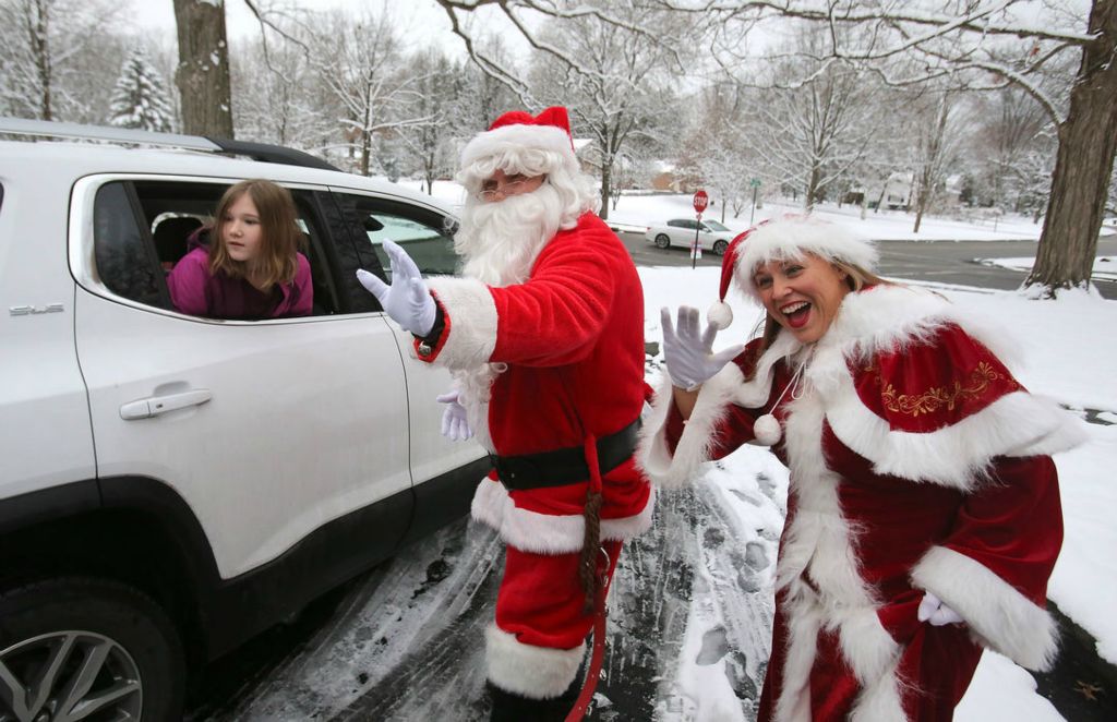 Feature - 3rd place - Santa and Mrs. Claus (Zeke and Becky Fernandez) wave to vehicles during a drive-through Christmas party hosted by Regina Coeli preschool teachers and staff in Alliance. The party was held at the home of Kelli Berry, pre-school director and teacher at the school. Looking on is Scarlett Stafford who attended with her sister Khloe Stafford.  Scott Heckel / The Repository