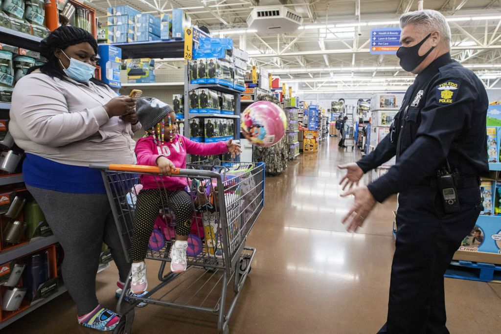 Feature - 1st place - Toledo police officer Jim Below (right) throws a ball with Demi Johnson, 2, as they take a break from shopping during the annual shopping with heroes event at the Walmart in Spring Meadows Place in Holland. (Rebecca Benson / The Blade) 