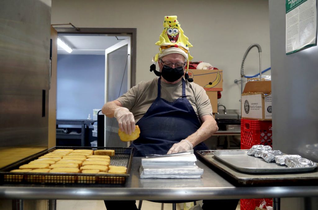 Feature - 3rd place - Karl Beem, substitute employee with food services, wraps slices of garlic bread in tin foil for students' hot lunch option  at Stevenson Elementary in Grandview Heights. Spacing requirements caused by the pandemic has resulted in students eating lunch in both the cafeteria and gym while no longer lining up for meals. Food services employees set out lunches, which are chosen by students at the beginning of the school day, labeled with each student's name in the cafeteria and outside classrooms to be picked up during lunch hour. (Shane Flanigan / ThisWeek Community News) 