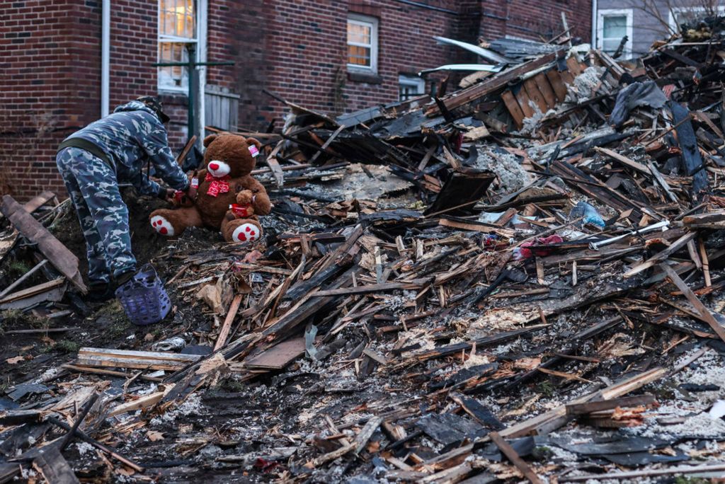 General News - 1st place - Mark Lockett places a teddy bear on the remains of a burned house for his grandson, 9-year-old Amare Lockett, who died in a house fire on Christmas Eve in Toledo. (Rebecca Benson / The Blade) 