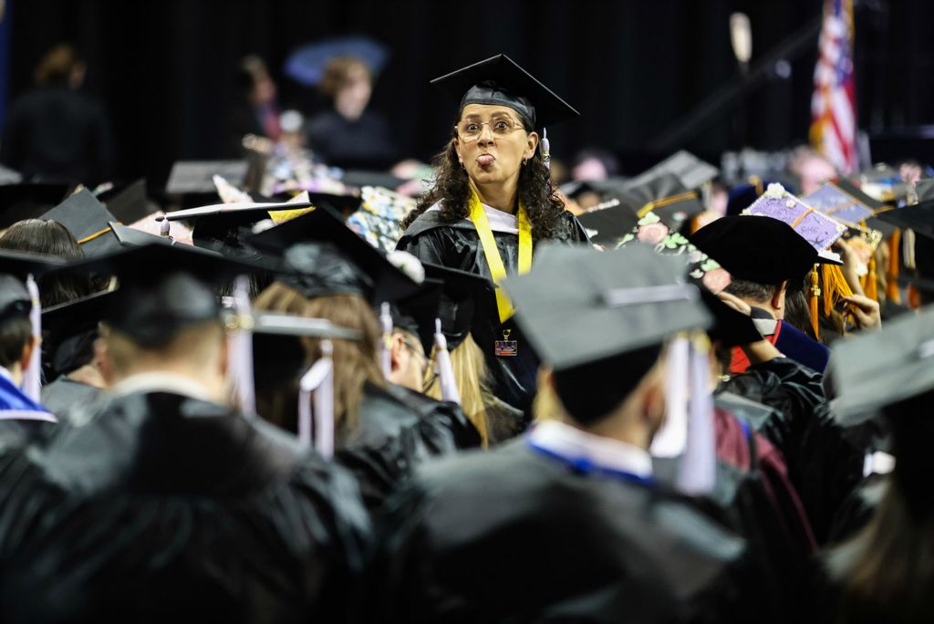 Feature - HM - Itzell Krauss sticks her tongue out at her family during the University of Toledo’s fall commencement ceremony at Savage Arena in Toledo. (Rebecca Benson / The Blade)