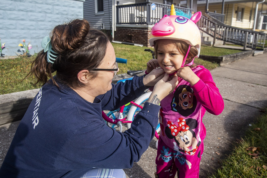 Feature - 1st place - Lacy Bowman helps her granddaughter Salecia Bowman, 3, put on her helmet to ride her new bike as they enjoy the warm Christmas Day weather in Toledo. (Rebecca Benson / The Blade)