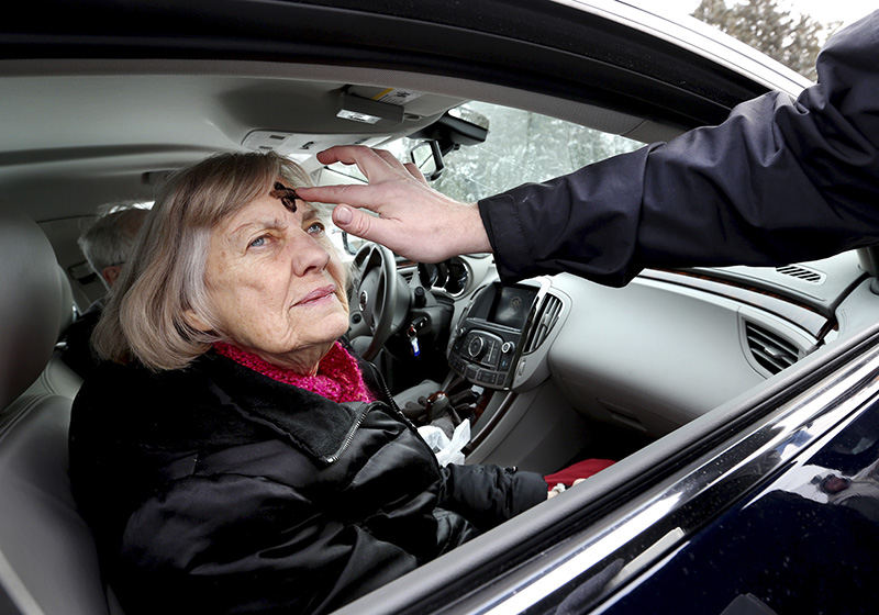 Feature - 3rd place - Pastor Grant Eckhart places ashes on Marilyn Elliott's forehead during drive-up Ash Wednesday at Advent Evangelical Lutheran Church in Upper Arlington.  (Fred Squillante / The Columbus Dispatch)