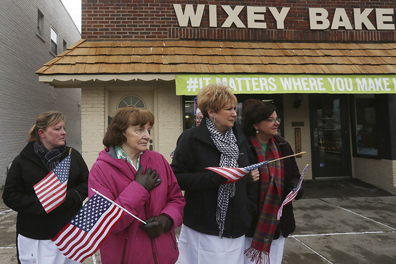 General News - 2nd place - Nancy McDermott, 84, center, keeps her hand over her heart as she and other mourners watch the funeral processional for Toledo Mayor D. Michael Collins pass by Wixey Bakery in South Toledo. After winding its way through the city, the processional ended at Toledo's Rosary Cathedral for a funeral Mass.  (Katie Rausch / The (Toledo) Blade)