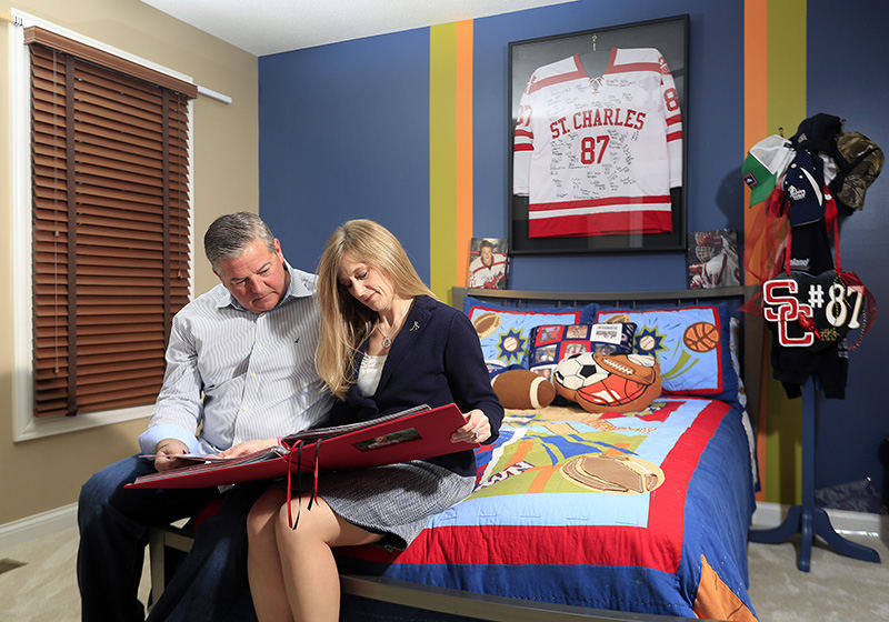 spStory - 2nd place - Lisa and Jim Knox look over a memory book of their son, Thomas, in his bedroom in their house in Westerville.  They lost Thomas, a freshmen hockey player for St. Charles, in his sleep of apparent heart failure on December 13, 2015. (Kyle Robertson / The Columbus Dispatch)