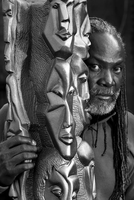 Portrait - 1st place - Sculptor Omar Shaheed poses with his sculpture, "Faces in the Crowd" in his backyard. After the fairly recent deaths of artists Aminah Robinson and Kojo Kamau, Omar is one of the leading black artists in central Ohio. (Fred Squillante / The Columbus Dispatch)