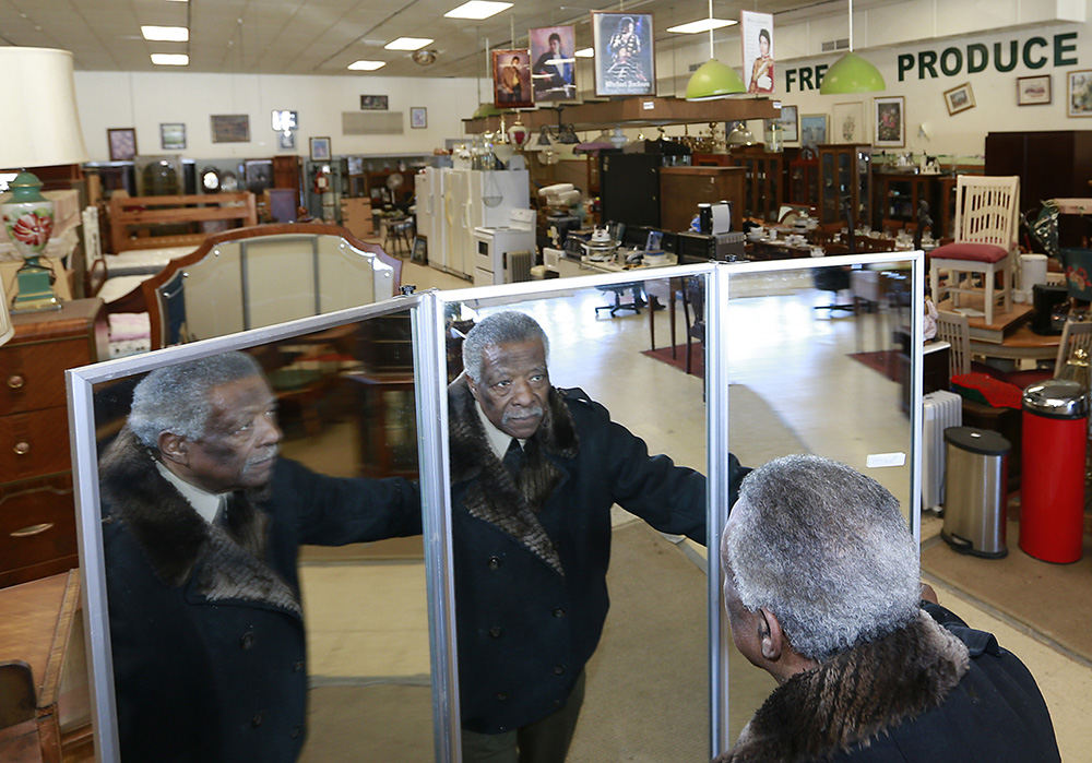 Portrait - 3rd place - Charles Dean, owner of Unique Furnishings Plus in the Southern Village shopping center, is reflected in a three way mirror as he unfolds it. Dean is moving his business to the old Elder Beerman location in the Upper Valley Mall.  (Bill Lackey / Springfield News-Sun)