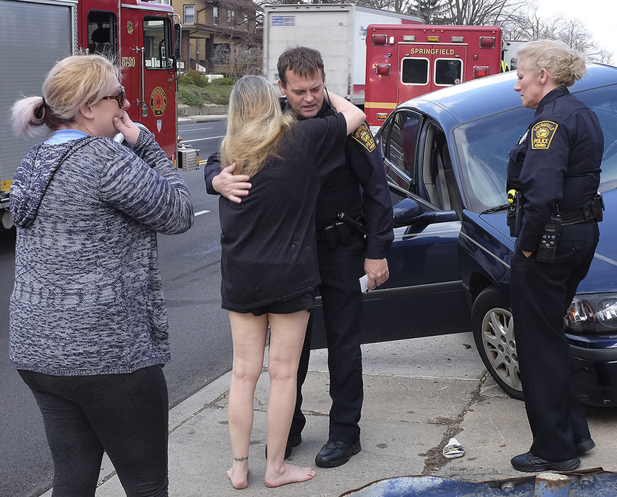 Spot News - 2nd place - Officer Andy Scott, of the Springfield Police Division, gets a hug from a family member of an accident victim on the scene of a two vehicle accident on North Limestone Street.  (Bill Lackey / Springfield News-Sun)