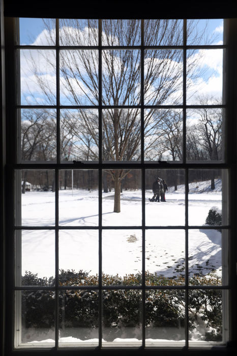 Feature - HM - Dog walkers make their way down a snowy trail as seen through a window in the Manor House of Wildwood Preserve Metropark. (Amy E. Voigt / The Blade)