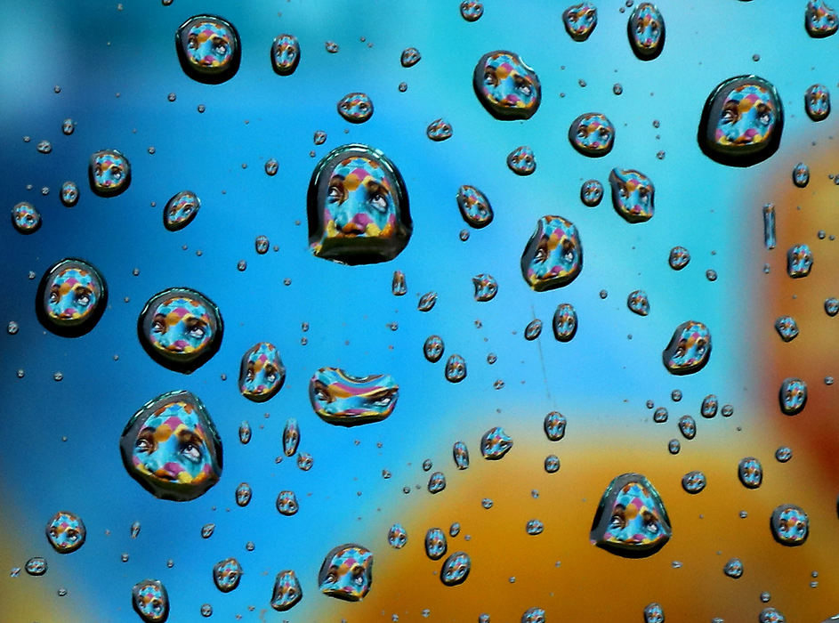 Feature - 1st placeA face, part of the mural on the side of the Springfield YMCA, is reflected in the rain drops on a car window, Feb. 6, 2019.  (Bill Lackey/Springfield News-Sun)