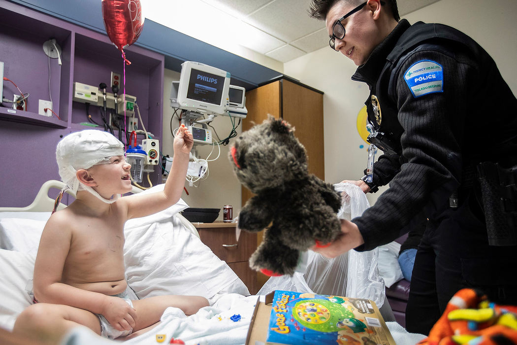 General News - 3rd placeMercy Health police officer Miami Box (right) hands Brayden Oakley, 4, a teddy bear as he shows her a toy from a game at Mercy Health Children’s Hospital in Toledo. Members of the Toledo Police Department and Mercy Health Police hand out teddy bears to children for Valentines Day.  (Rebecca Benson/The Blade)