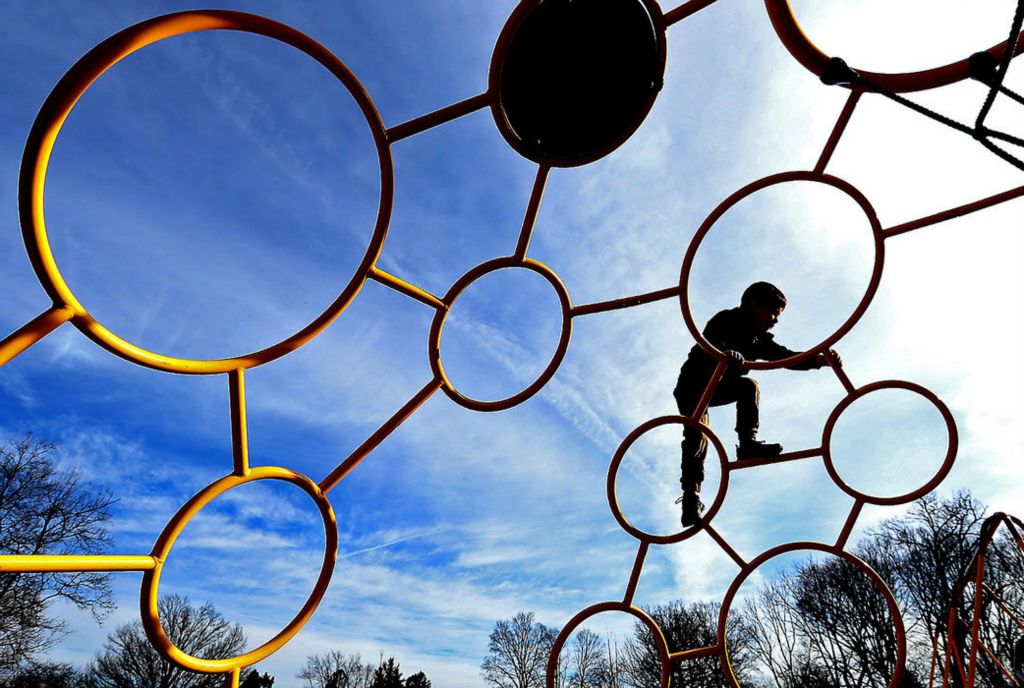 Feature - 3rd place - A child plays on the playground at Smith Park in New Carlisle as he and his family take advantage of the unseasonably warm temperatures and sunshine.  (Bill Lackey / Springfield News-Sun)