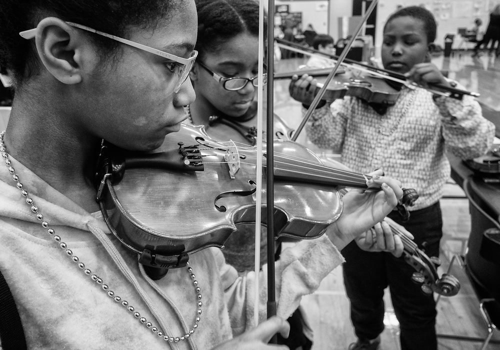 Story - 3rd place - From left Marissa Smith, 13, her sister Kira Smith, 11, and Robert Pasker-Sisson, 10, practice playing violas and violins at the music display during Wakanda Night at Rogers High School in Toledo. Wakanda Night is an academic and resource fair for students to engage in college exploration, STEM activities, art demonstrations and music performances.  (Jeremy Wadsworth / The Blade)