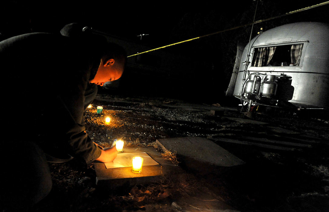 General News - 3rd place - Chase Edman, 13, signs the picture he drew in memory of Clark County Ohio Sheriff's Deputy Suzanne Waughtel Hopper as he leaves it outside the bullet riddled Enon Beach trailer where she was killed in a shoot out New Years Day.  Chase said he met Deputy Hopper when she was the D.A.R.E. officer at his school.  (Bill Lackey / Springfield News-Sun)